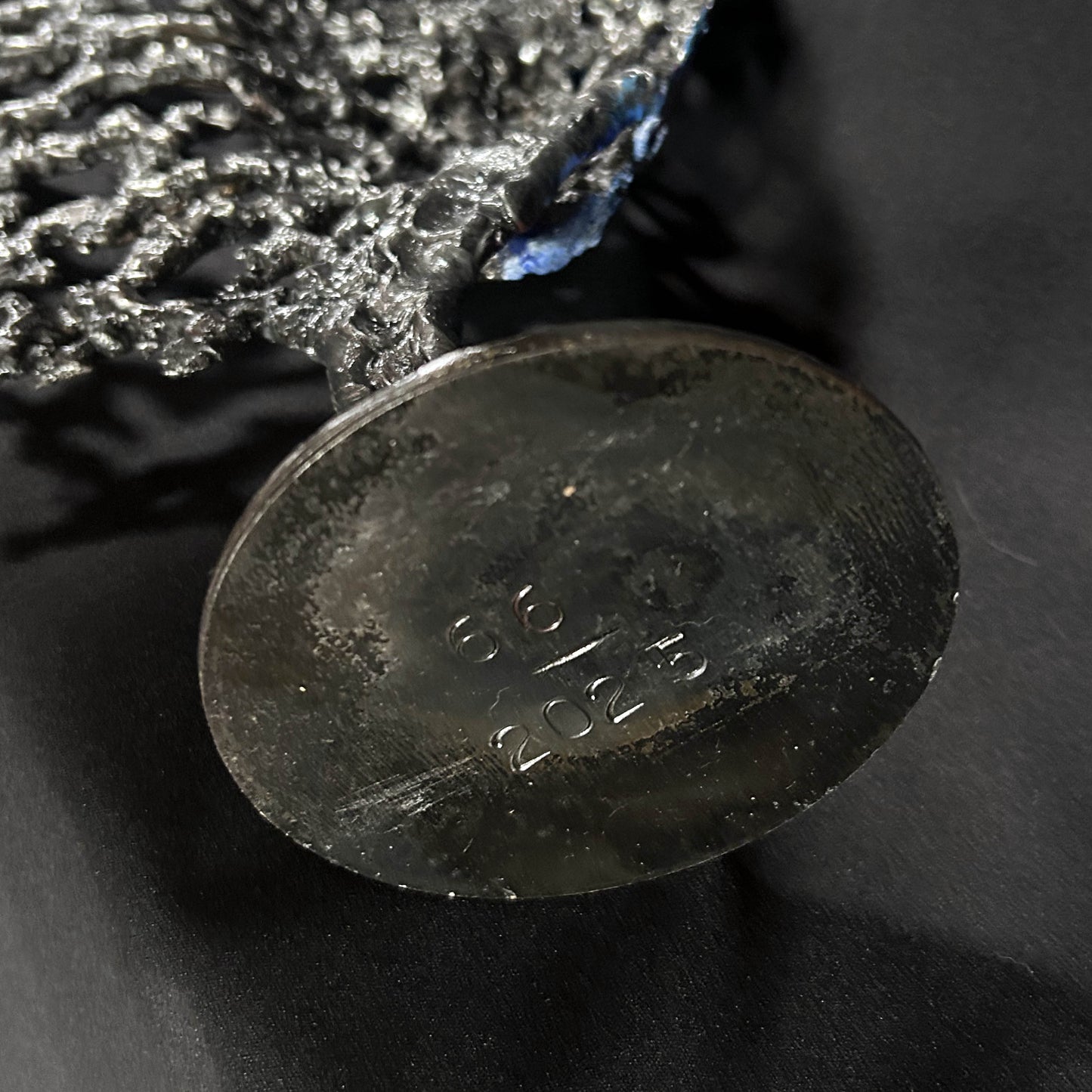 Sculpture de Philippe Buil représentant un visage humain en dentelle d'acier et bronze. Le côté gauche du visage est coloré avec des pigments bleus et rouges, tandis que le côté droit se transforme en une structure métallique ajourée et arborescente.