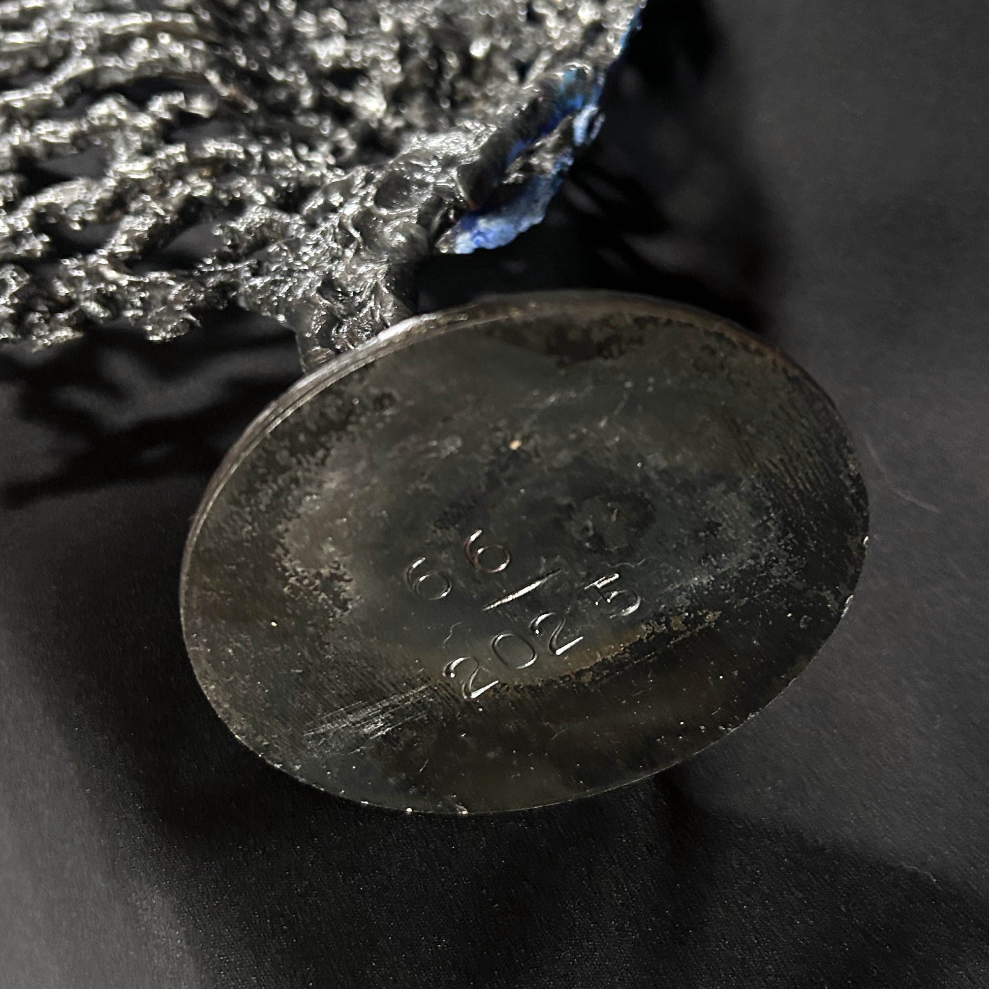 Sculpture de Philippe Buil représentant un visage humain en dentelle d'acier et bronze. Le côté gauche du visage est coloré avec des pigments bleus et rouges, tandis que le côté droit se transforme en une structure métallique ajourée et arborescente.