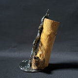 Sculpture contemporaine représentant une salamandre en dentelle de métal (acier), fixée sur un socle métallique circulaire et appuyée contre un morceau de bois naturel, œuvre de Philippe Buil, sur fond sombre.