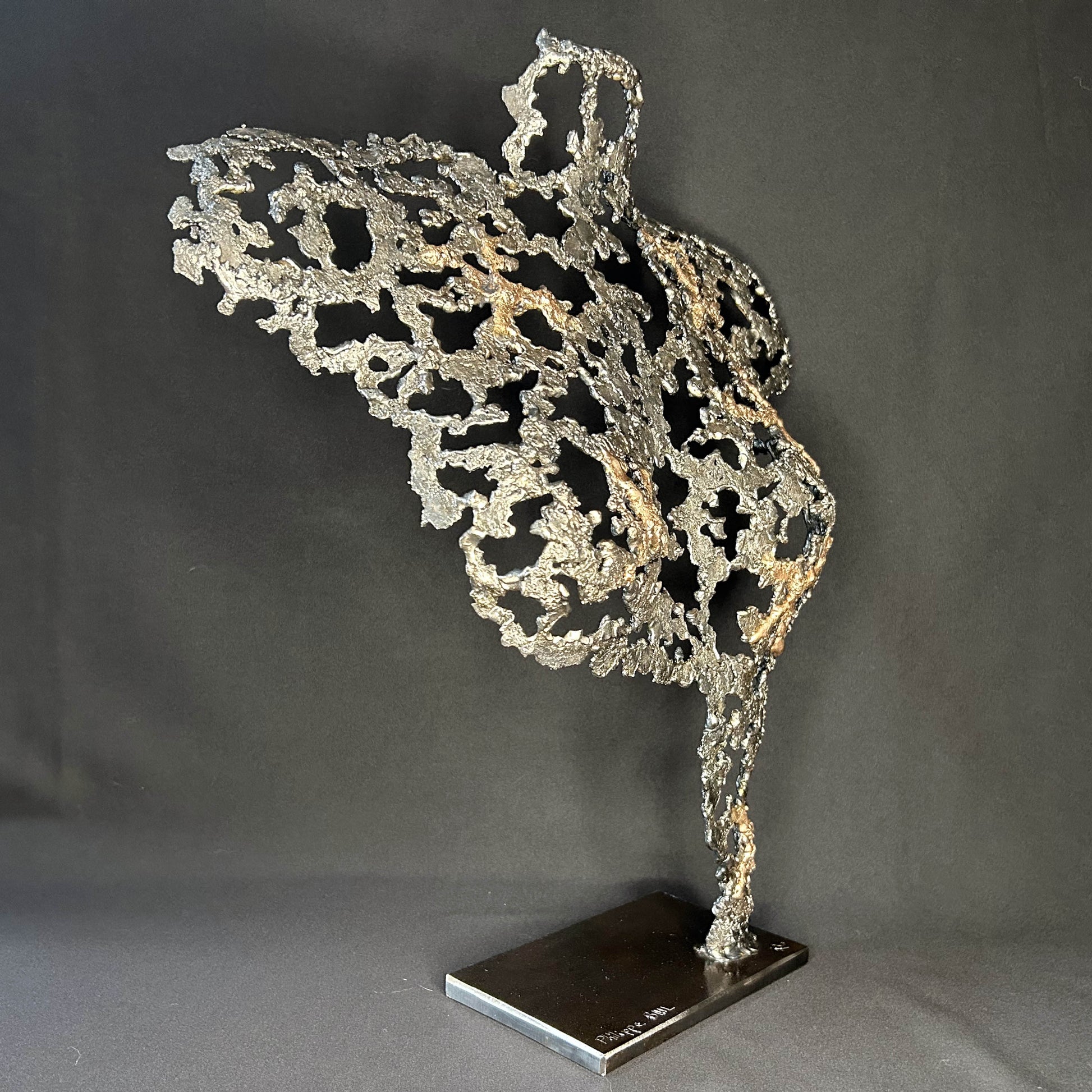 Sculpture contemporaine Belisama Le Souffle de Philippe Buil, buste de femme à taille réelle en dentelle de métal acier et bronze avec étoiles fondues, vue de profil sur fond sombre.