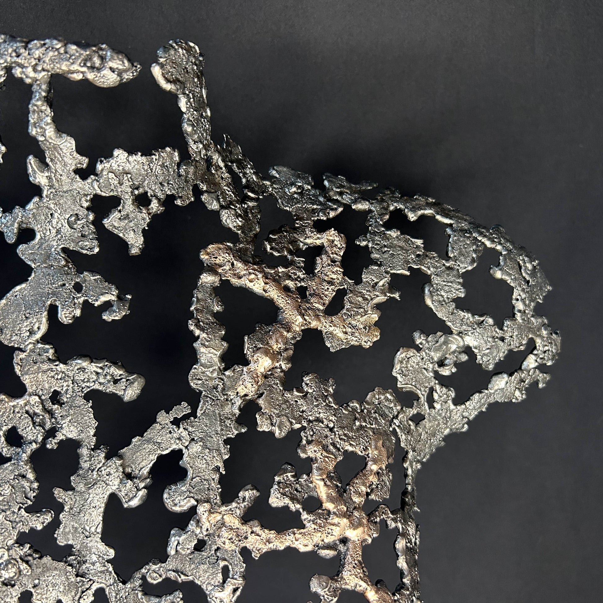 Détail Sculpture contemporaine Belisama Le Souffle de Philippe Buil, buste de femme à taille réelle en dentelle de métal acier et bronze avec étoiles fondues,  sur fond sombre.