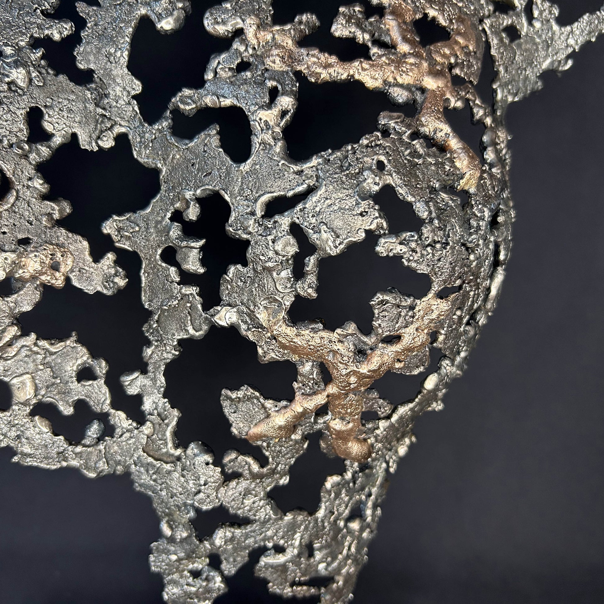 Détail Sculpture contemporaine Belisama Le Souffle de Philippe Buil, buste de femme à taille réelle en dentelle de métal acier et bronze avec étoiles fondues,  sur fond sombre.